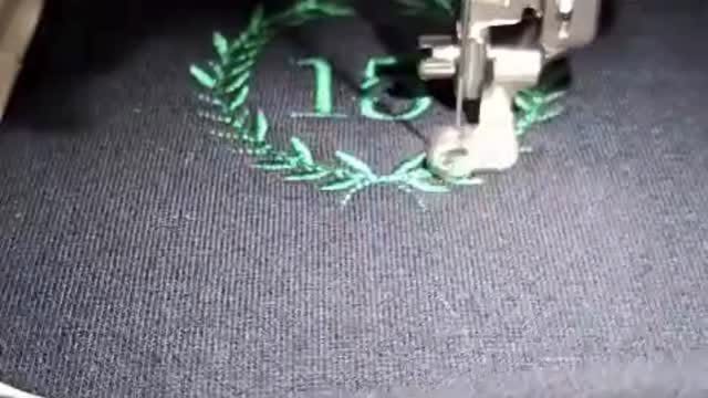 A laurel wreath and the number 15 being embroidered