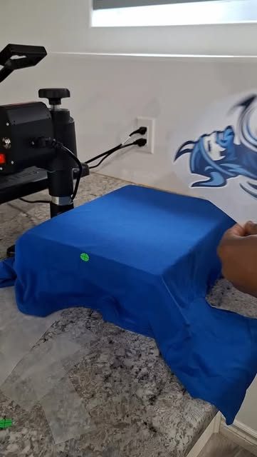 A blue shirt being loaded onto the heat press